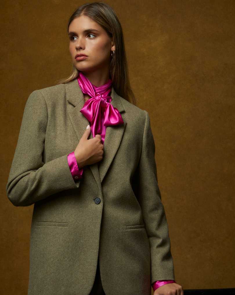 Model wearing olive tweed blazer with hot pink satin pussy bow blouse, Helen McAlinden AW25