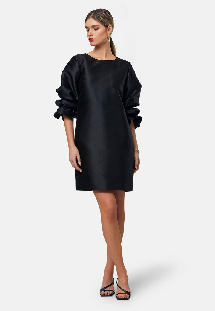 Step into the spotlight with Aurora, a chic short-shift dress in bold black. This stylish piece features a statement puff-ball sleeve, side seam pockets, and falls just above the knee. Crafted from a silk blend taffeta. Make a grand entrance with Aurora, perfect for a soiree or formal dressing.