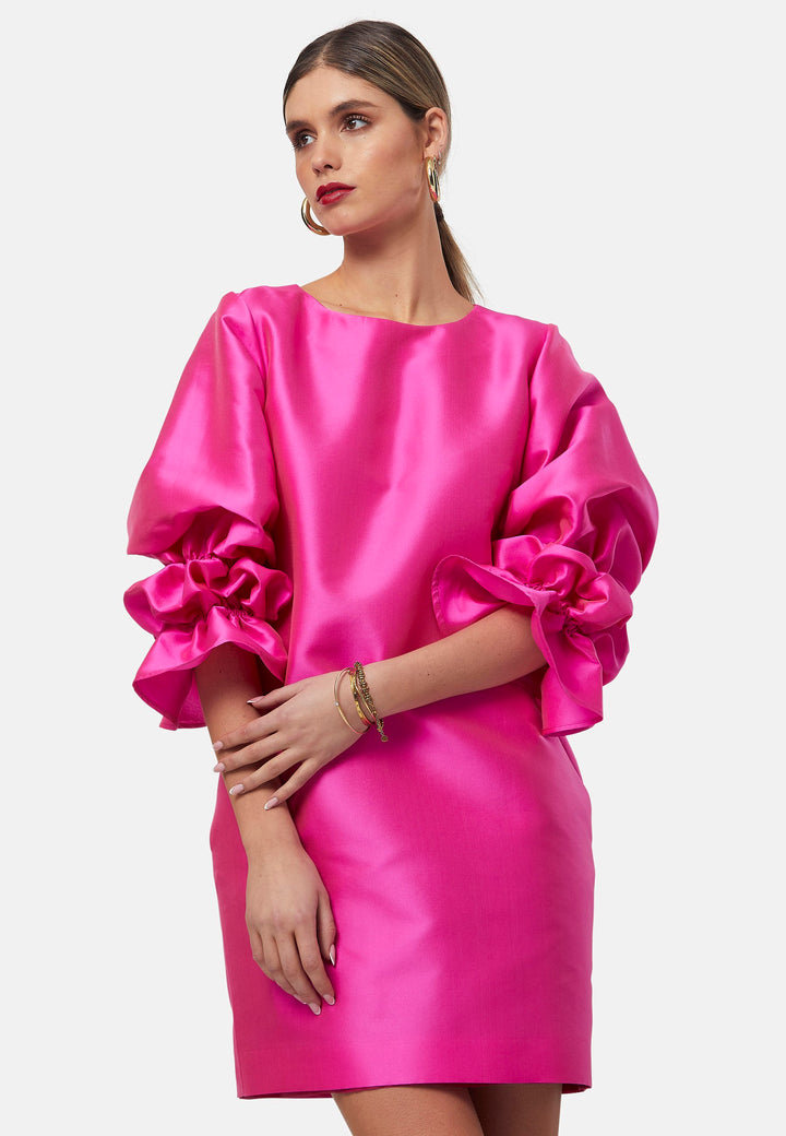 Step into the spotlight with Aurora, a chic short-shift dress in bold Fuchsia. This feminine piece features a statement double puff-ball sleeve, side seam pockets, and falls just above the knee. Crafted from a shimmering silk blend taffeta. Make a grand entrance with Aurora, perfect for a soiree or formal dressing.