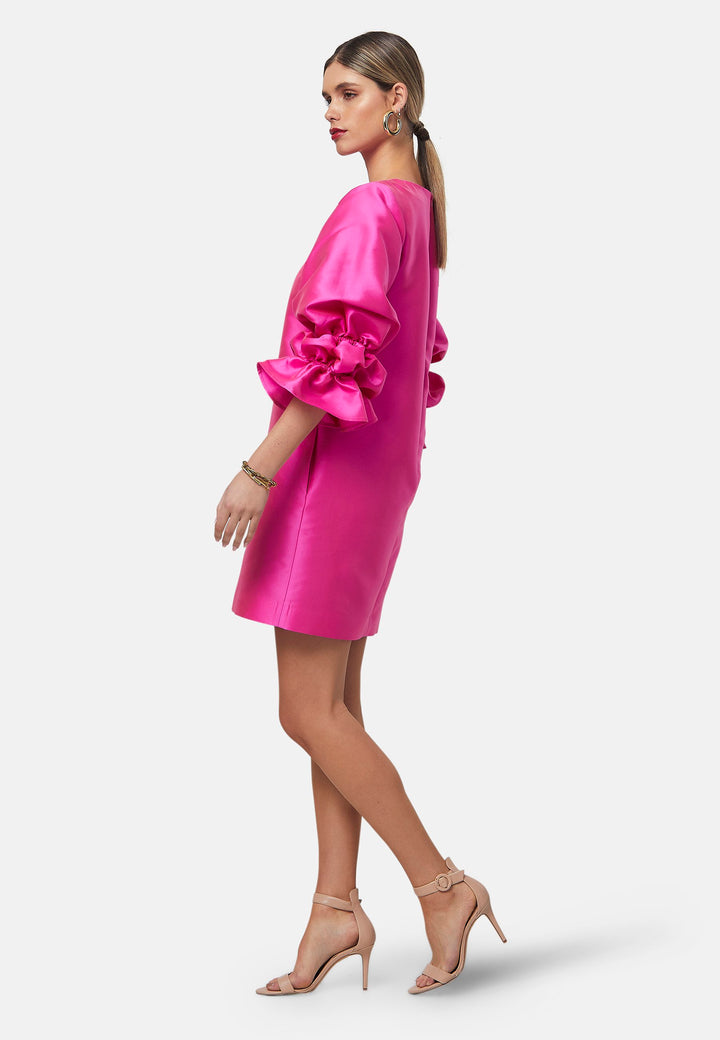 Step into the spotlight with Aurora, a chic short-shift dress in bold Fuchsia. This feminine piece features a statement double puff-ball sleeve, side seam pockets, and falls just above the knee. Crafted from a shimmering silk blend taffeta. Make a grand entrance with Aurora, perfect for a soiree or formal dressing.