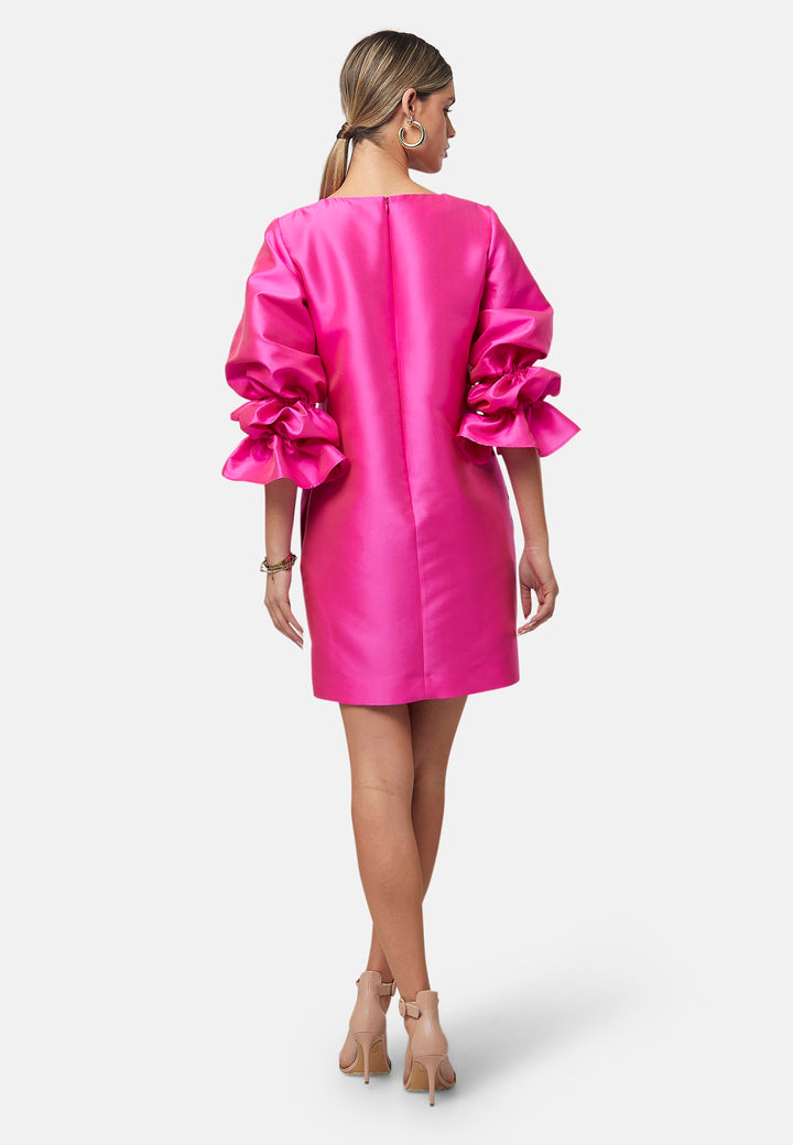 Step into the spotlight with Aurora, a chic short-shift dress in bold Fuchsia. This feminine piece features a statement double puff-ball sleeve, side seam pockets, and falls just above the knee. Crafted from a shimmering silk blend taffeta. Make a grand entrance with Aurora, perfect for a soiree or formal dressing.