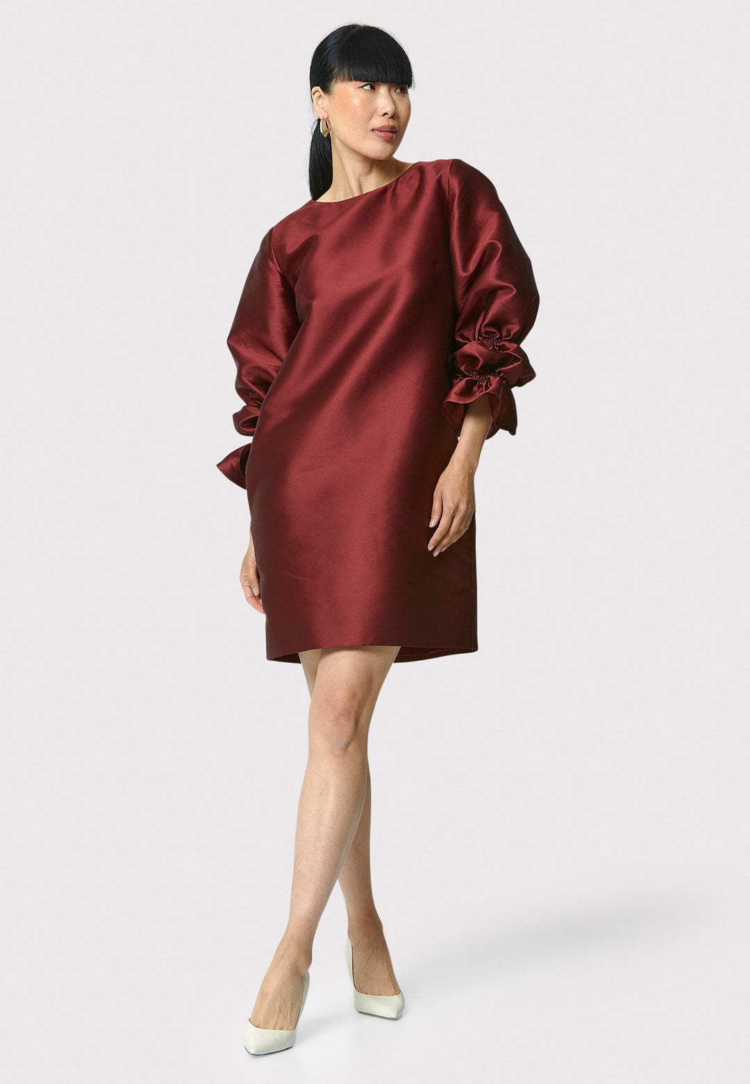 Step into the spotlight with Aurora, a chic short shift dress in a stunning mahogany red hue. This stylish piece features a statement puff-ball sleeve , side seam pockets, and falls above the knee. Crafted from a silk blend taffeta. Make a grand entrance with Aurora.