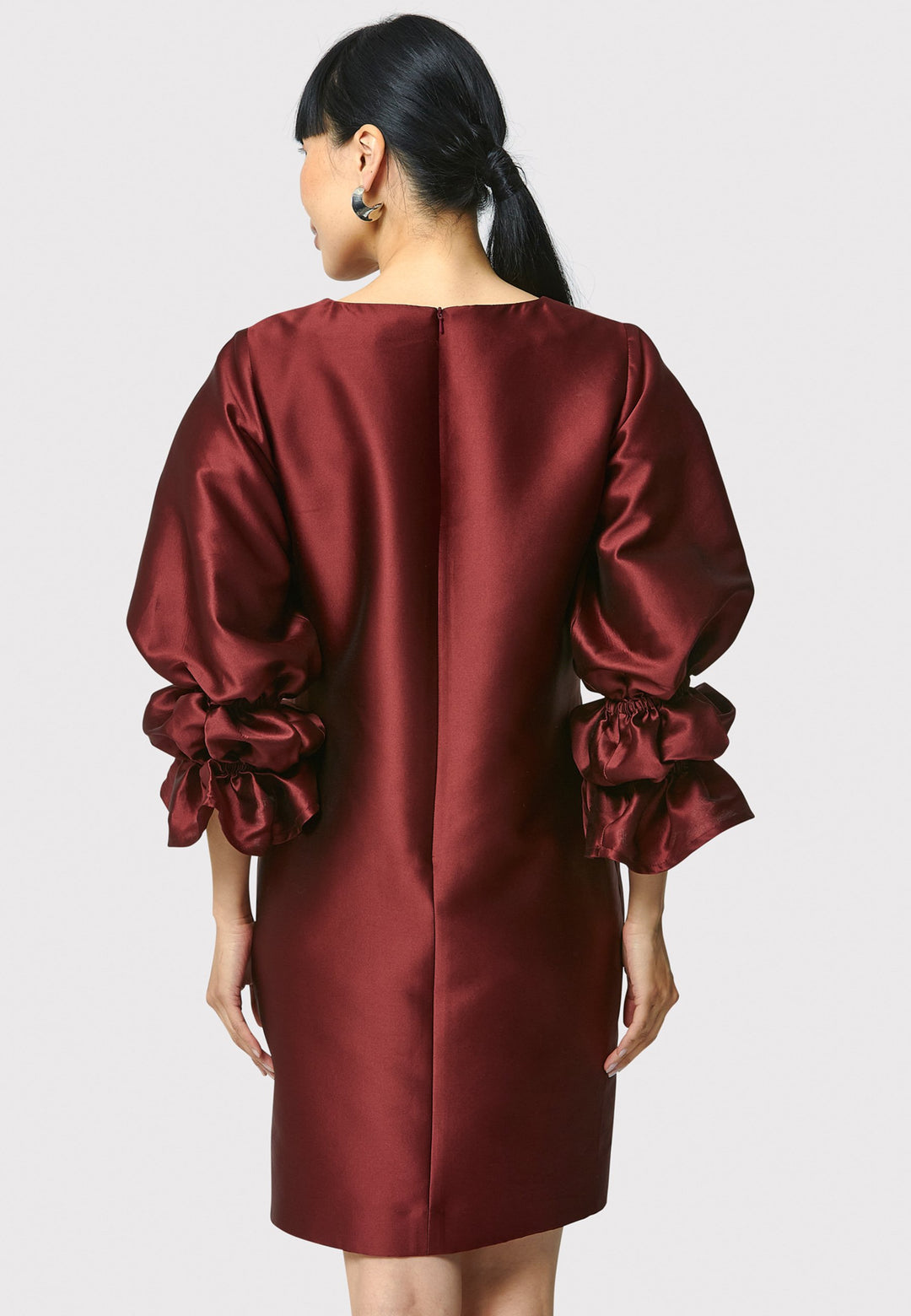 Step into the spotlight with Aurora, a chic short shift dress in a stunning mahogany red hue. This stylish piece features a statement puff-ball sleeve , side seam pockets, and falls above the knee. Crafted from a silk blend taffeta. Make a grand entrance with Aurora.