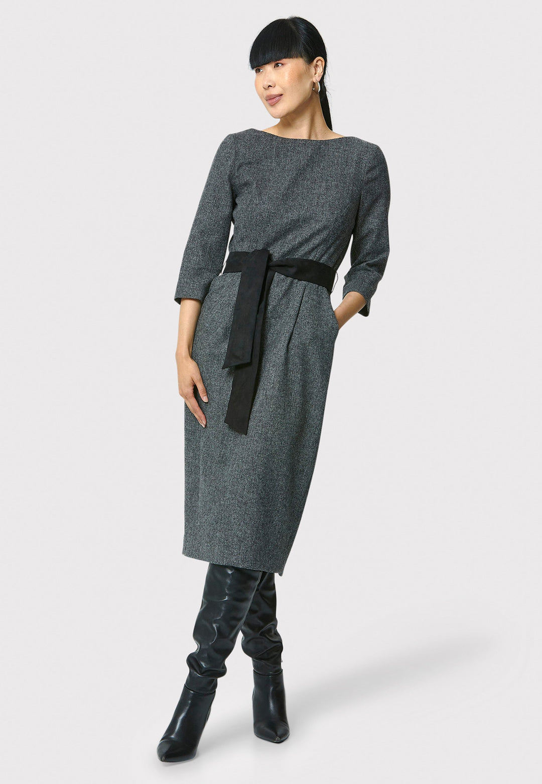 Caroline, a classic Helen McAlinden dress in charcoal grey. Crafted from a soft-touch wool blend, this bodycon dress features a bateau neckline, three-quarter sleeves and the front pleats allow the fabric to fall softly over the hip. The reversible belt with black suede on one side and self-fabric on the other for versatile styling. The dress is completed with side pockets and a back slit for added ease of movement.