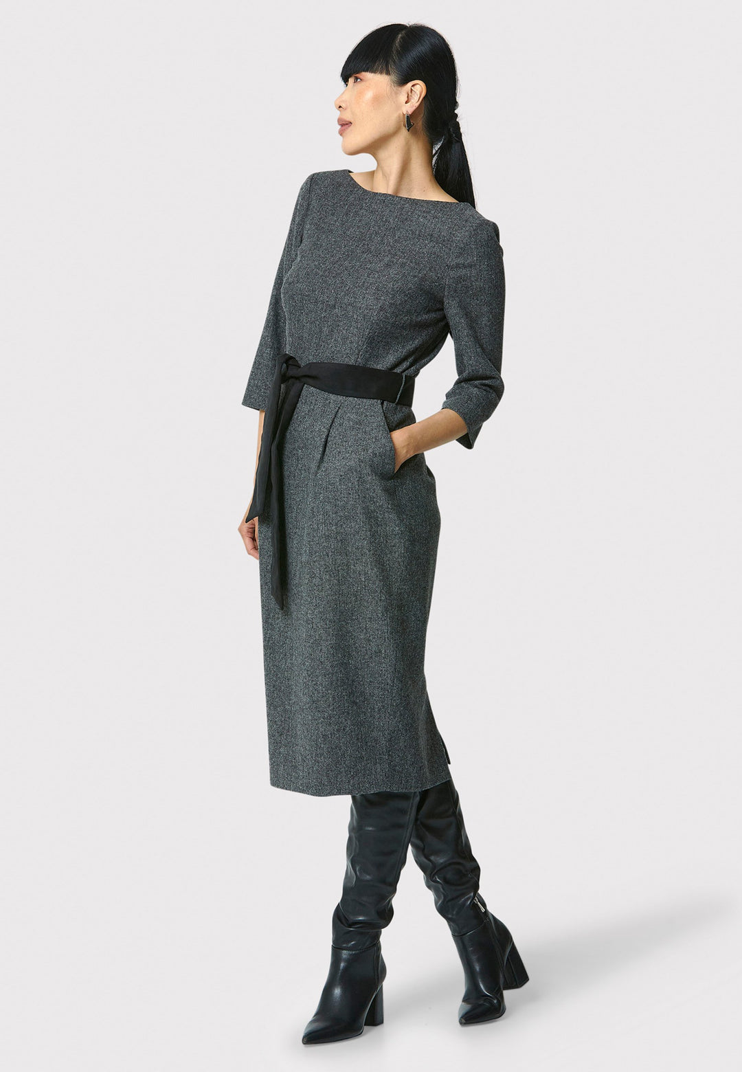 Caroline, a classic Helen McAlinden dress in charcoal grey. Crafted from a soft-touch wool blend, this bodycon dress features a bateau neckline, three-quarter sleeves and the front pleats allow the fabric to fall softly over the hip. The reversible belt with black suede on one side and self-fabric on the other for versatile styling. The dress is completed with side pockets and a back slit for added ease of movement.