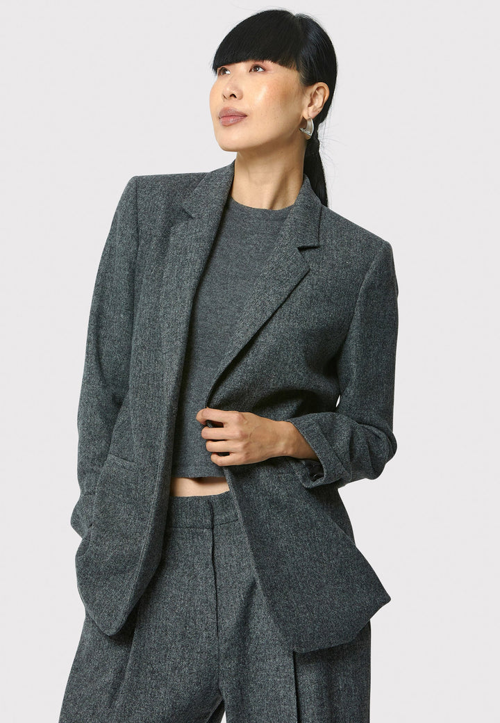 The Cassie boyfriend blazer in charcoal grey, crafted from a soft-touch wool blend, is an investment-worthy staple. Its minimalist design features a single button fastening, an oversized and slightly boxy silhouette, making it ideal for transeasonal outerwear. Complete a modern ensemble by pairing it with the coordinating Lyra pant.