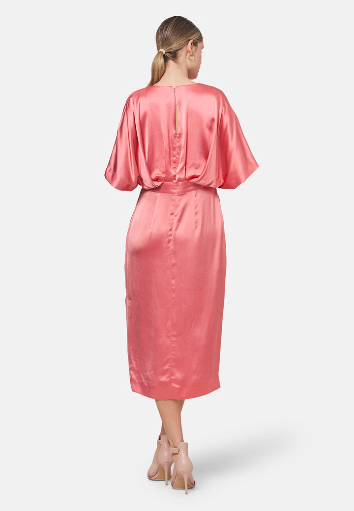 Eabha, the coral rose dress with quiet glamour. Cut from fluid, silk-touch satin, it frames the neckline with a gentle V and draped kimono sleeves, then gathers into under-bust pleats that flatter the waistline. The column midi skirt skims beautifully with discreet side seam pockets and slits for ease, finished with a neat keyhole back. Just add barely-there heels and gold jewellery.