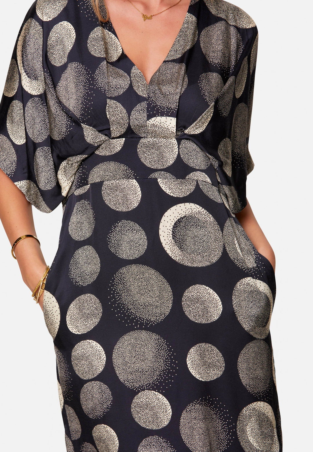 Eabha, the print dress with quiet drama. In fluid, silk-touch navy satin scattered with ivory lunar dots, it features a soft V-neckline, kimono sleeves and under-bust pleats that flatter the waistline. The column midi skirt is finished with discreet side seam pockets and a slit for ease, plus a neat keyhole back. Just add heels and minimal jewellery.