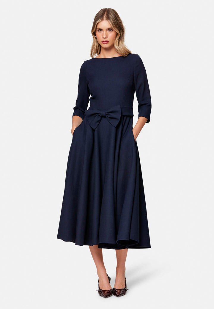 Eva, the modern fit-and-flare. Inspired by Hollywood glamour, this silhouette features a fitted bodice, flared skirt and a flattering scoop back. Designed with a round neckline, side seam pockets and a centre-back zip. The detachable bow belt adds a versatile finishing touch.