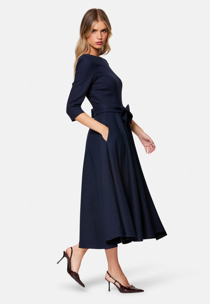 Eva, the modern fit-and-flare. Inspired by Hollywood glamour, this silhouette features a fitted bodice, flared skirt and a flattering scoop back. Designed with a round neckline, side seam pockets and a centre-back zip. The detachable bow belt adds a versatile finishing touch.