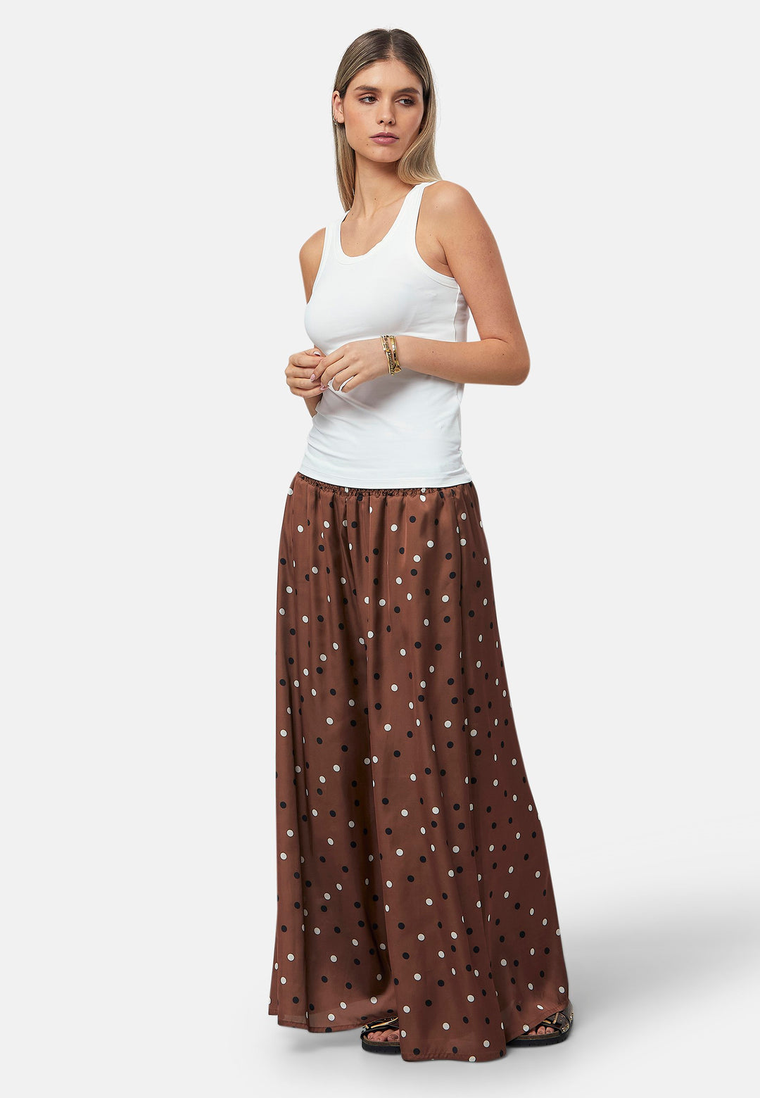 The Imogen wide-leg trousers in a brown base, black and white polkadot print. Prioritizing comfort with an elasticated gathered waistband. The pattern adds a touch of fun to this bestseller silhouette.