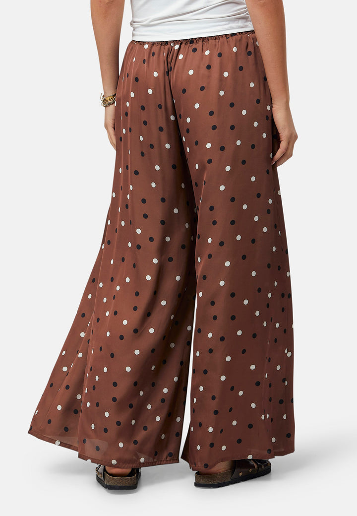 The Imogen wide-leg trousers in a brown base, black and white polkadot print. Prioritizing comfort with an elasticated gathered waistband. The pattern adds a touch of fun to this bestseller silhouette.