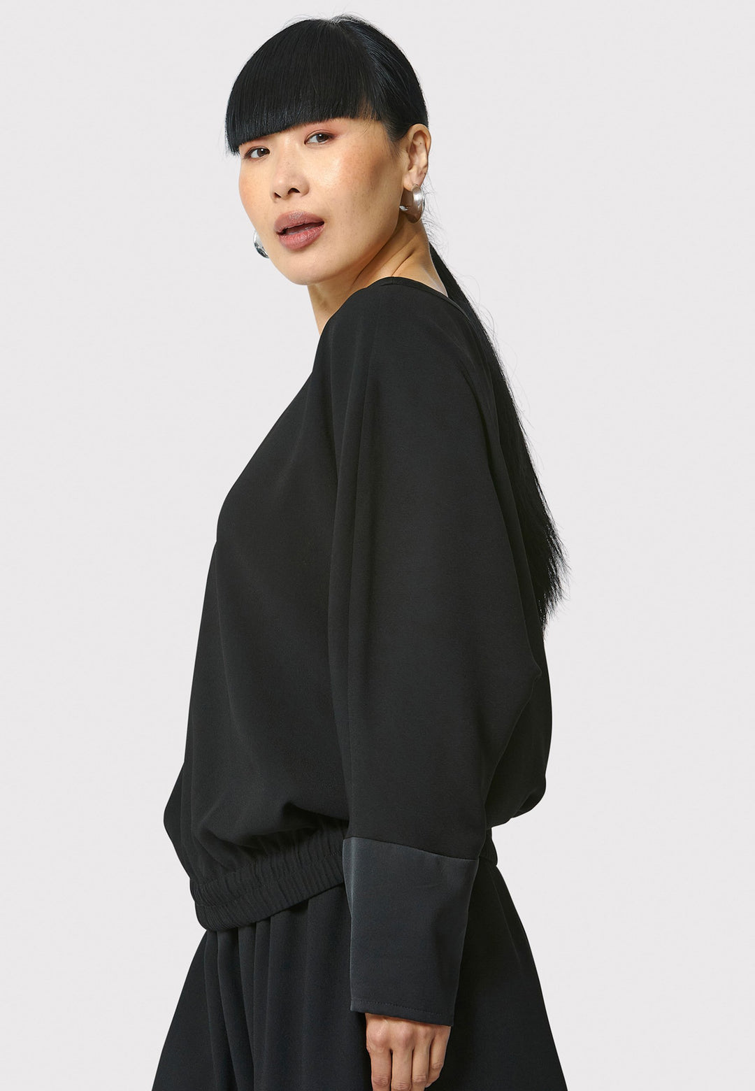 Lal, black top in fluid satin back crepe. A relaxed fit, elastic waistband, Dropped Shoulder sleeves, and satin cuffs. Wear with the coordinating Deliliah or Imogen Pant.