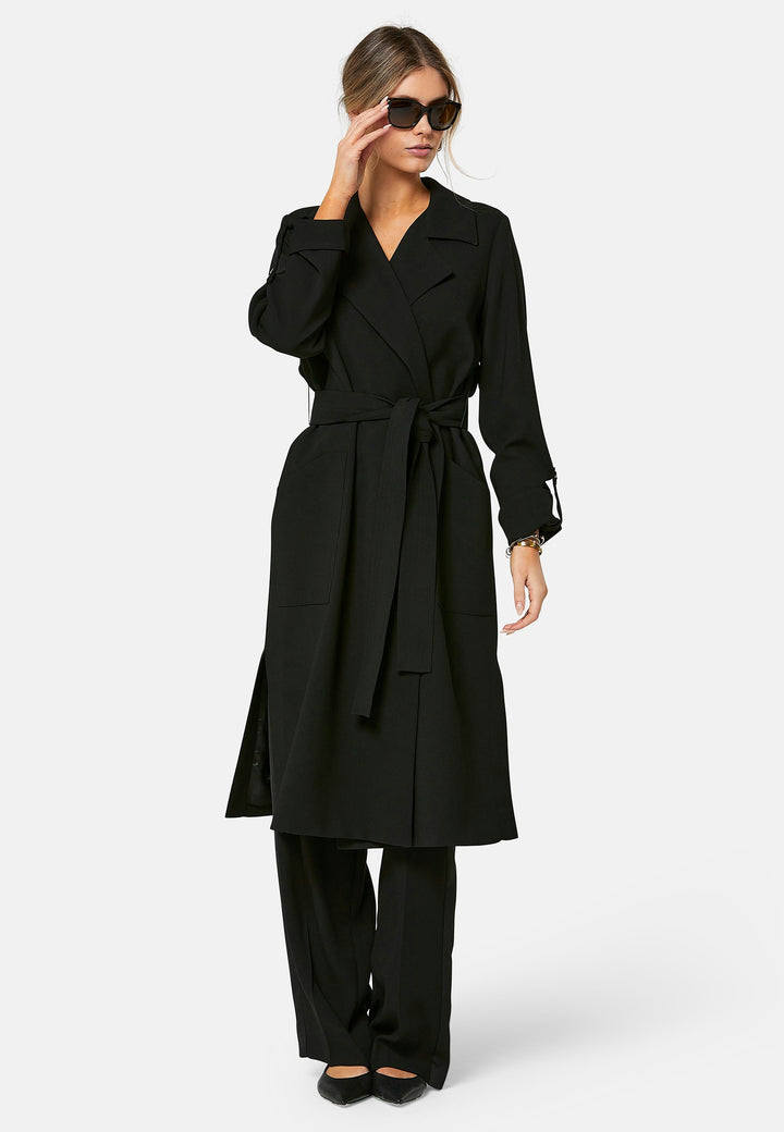 Lydiah, black trench coat in a fluid satin back crepe. This coat features a relaxed, flowing silhouette, a self-tie belt, and front pockets. The design includes buttoned cuffs and a wide lapel. Pair with coordinating trouser for a chic monochromatic look.