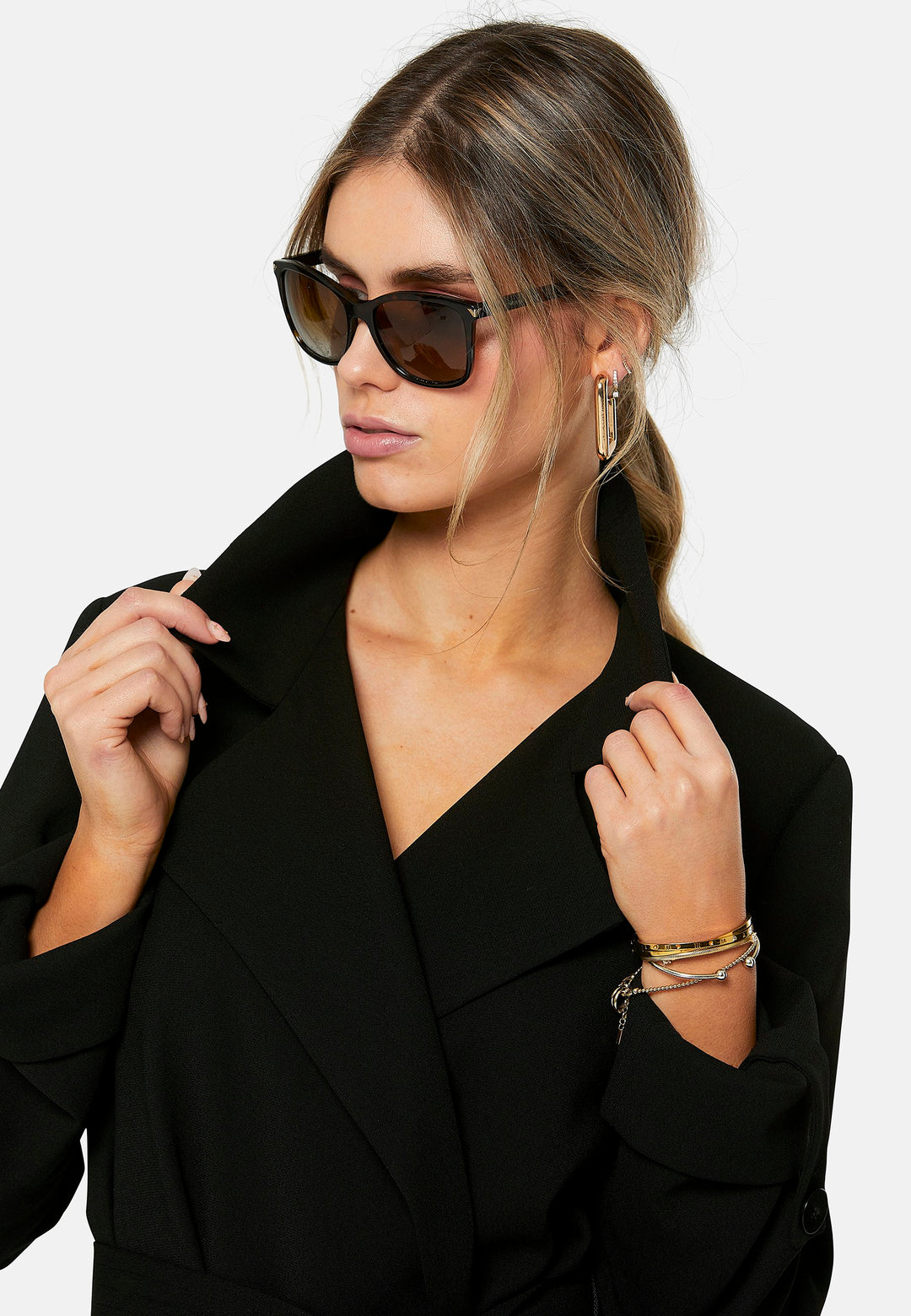 Lydiah, black trench coat in a fluid satin back crepe. This coat features a relaxed, flowing silhouette, a self-tie belt, and front pockets. The design includes buttoned cuffs and a wide lapel. Pair with coordinating trouser for a chic monochromatic look.