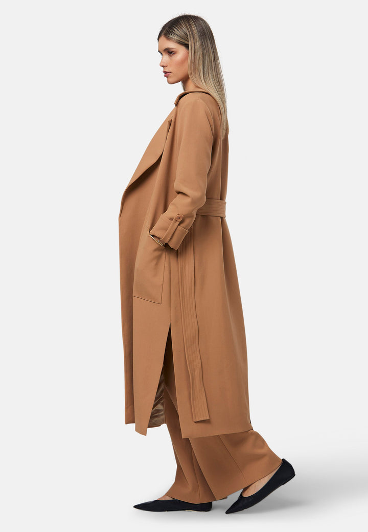 The Lydiah Coat is a minimalist trench style in camel. This coat features a relaxed, straight silhouette with a detachable self-tie belt, and front patch pockets. The design includes buttoned turn back cuffs and a wide lapel. Pair with our coordinating Lyra trouser for a chic monochromatic look.