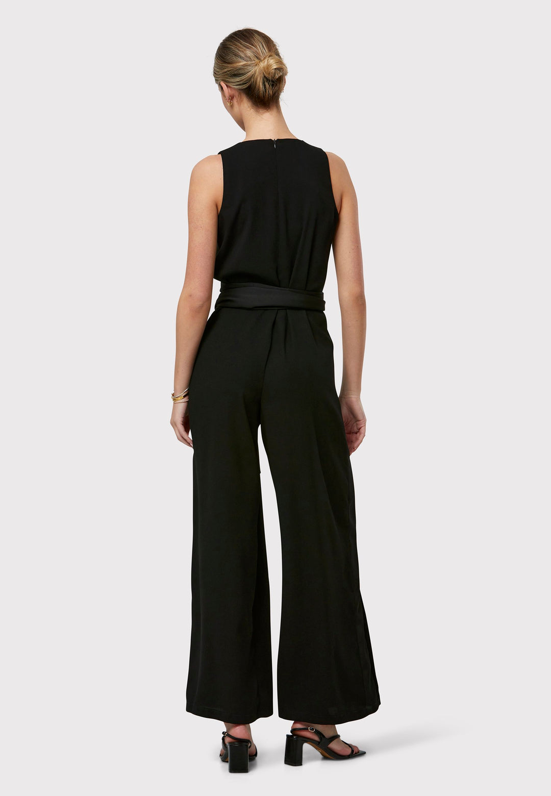 Marie-Claire, a sleeveless black jumpsuit in fluid satin back crepe. Featuring a wide-leg silhouette and satin stripes on the side seams. It comes with a detachable self-fabric belt that can be used to cinch the waist or worn around the neck. Includes practical side pockets for added convenience. Perfect for relaxed yet sophisticated evening dressing.