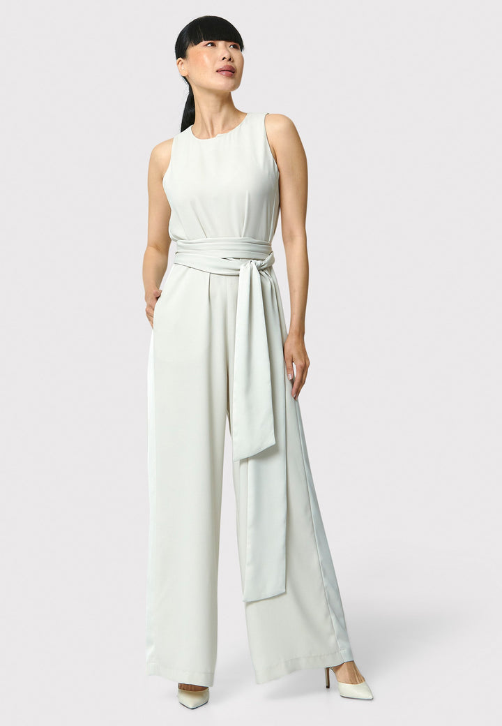 Marie-Claire, a sleeveless stone jumpsuit in fluid satin back crepe. Featuring a wide-leg silhouette and satin stripes on the side seams. It comes with a detachable self-fabric belt that can be used to cinch the waist or worn around the neck. Includes practical side pockets for added convenience. Perfect for relaxed yet sophisticated evening dressing.