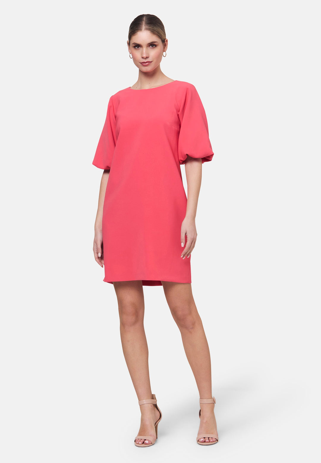 Mia, a chic short-shift dress in a fun watermelon pink hue. This feminine piece features a timeless silhouette with voluminous three-quarter puff sleeves and a round neckline. Its clean lines and relaxed fit make it ideal for both daytime outings and evening occasions.
