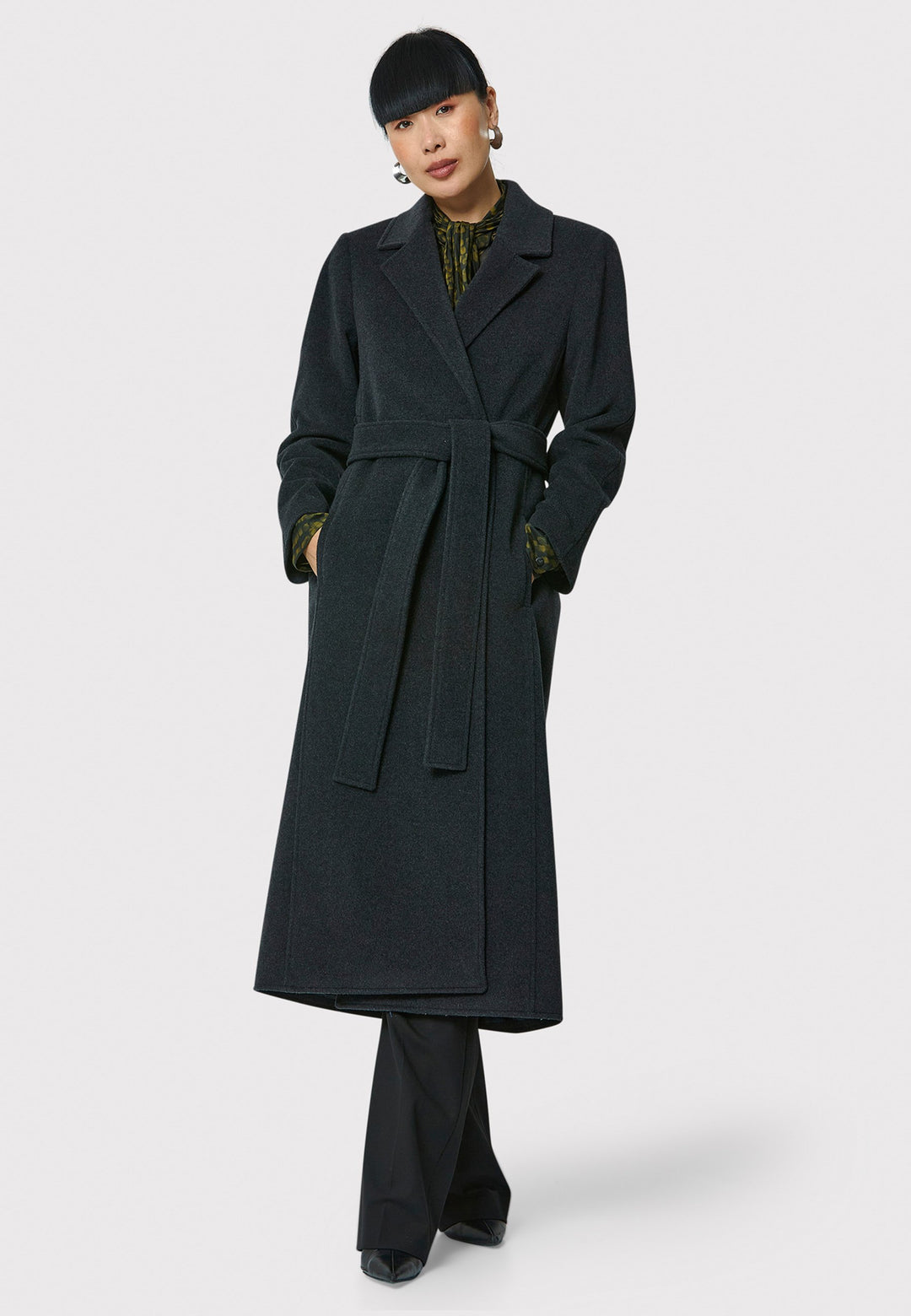 The Mikaela Charcoal Grey Coat, crafted from a luxurious blend of wool and cashmere, offers both style and versatility. This long duster coat features a classic collar and revere, button closure and practical side seam slits. Wear it straight for a relaxed silhouette, or cinch the waist with the matching self-fabric belt for a more defined shape. Complete with side seam pockets, this coat is a refined addition to your outerwear collection.