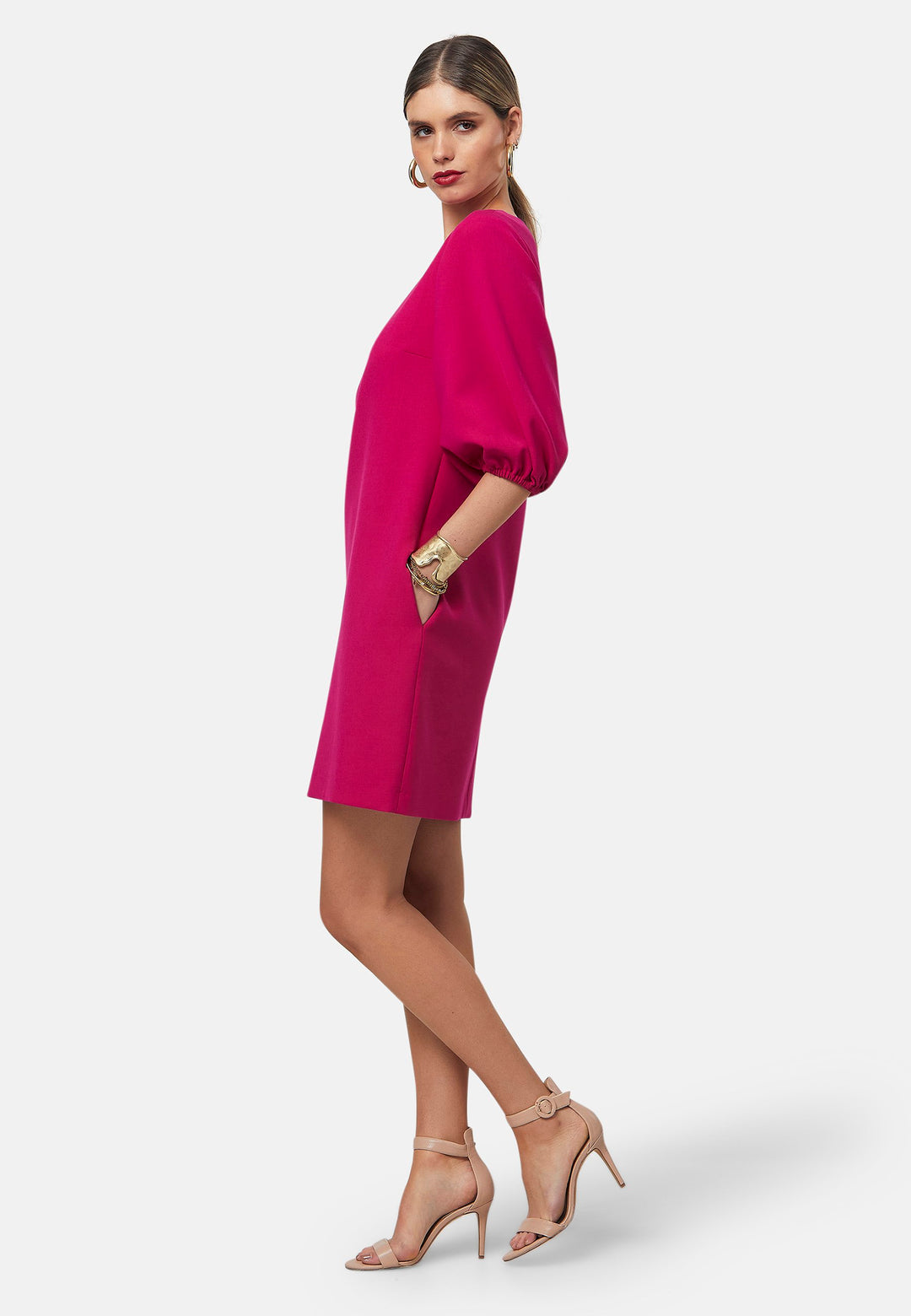 Mila, a chic short-shift dress in bold Fuchsia. This feminine piece features a timeless silhouette with voluminous three-quarter puff sleeves and a round neckline.