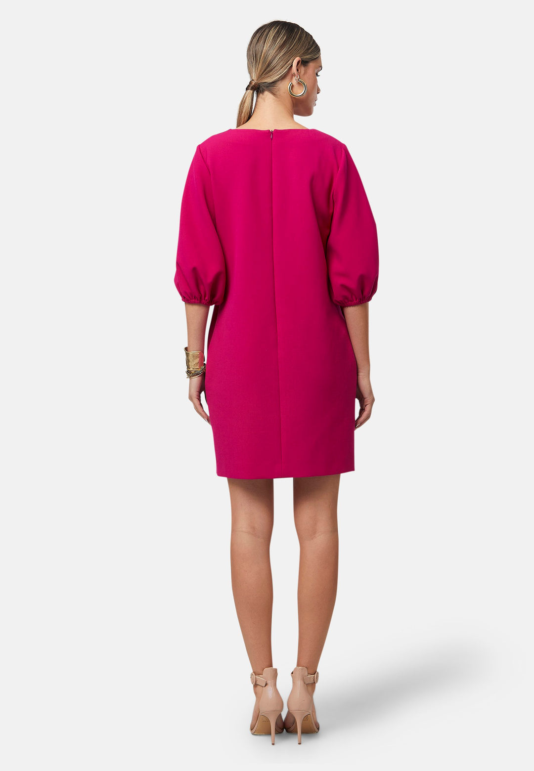 Mila, a chic short-shift dress in bold Fuchsia. This feminine piece features a timeless silhouette with voluminous three-quarter puff sleeves and a round neckline.