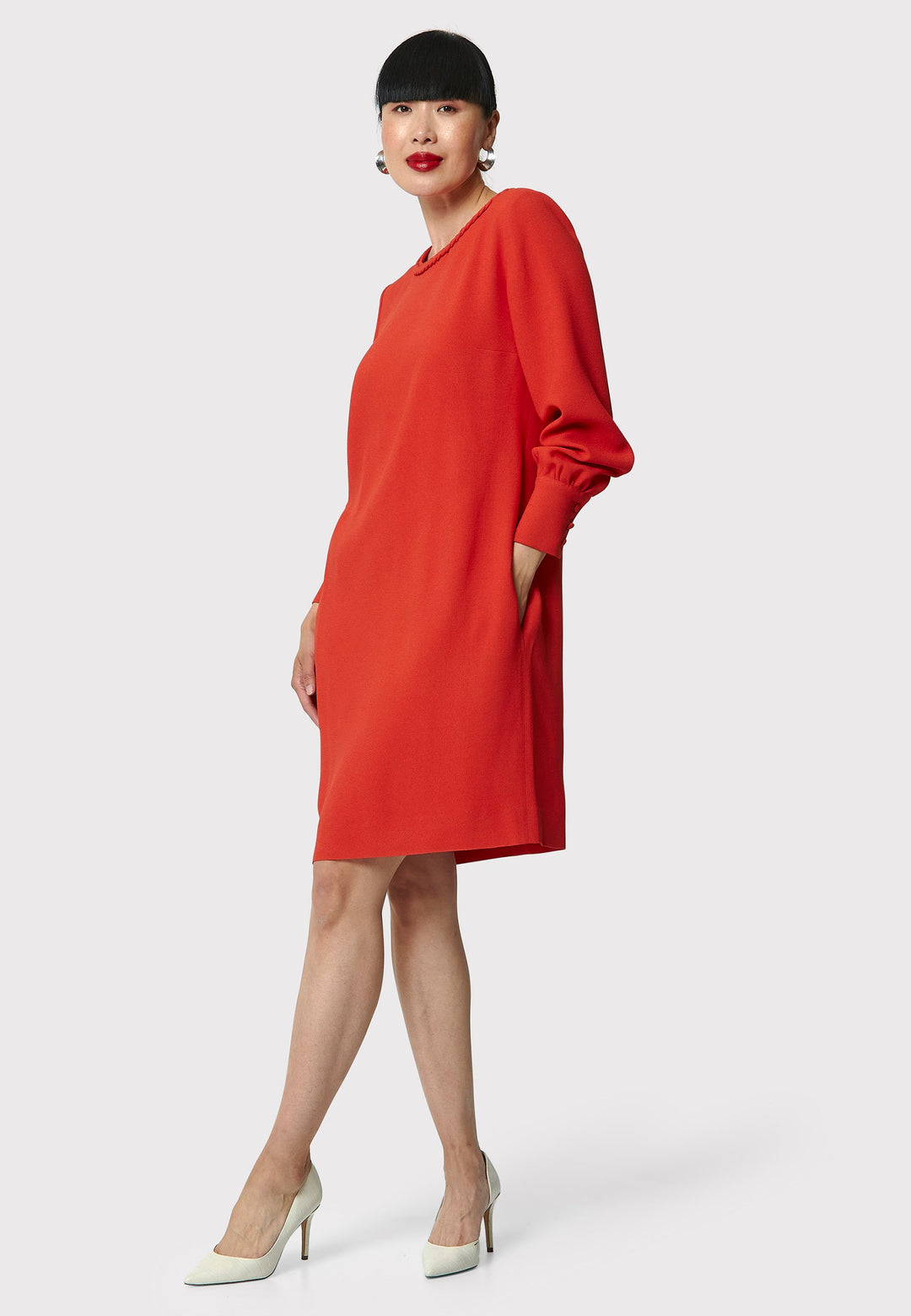 The Rachel Shift Dress is crafted in a vibrant burnt orange acetate and viscose blend crepe. This modern shift dress features a round neckline trimmed with an elegant plait trim. The relaxed-fit sleeves gather softly into buttoned cuffs, adding a refined touch. With convenient side pockets and a knee-length skirt, this dress is both stylish and practical. Perfect for work, wine or dining.