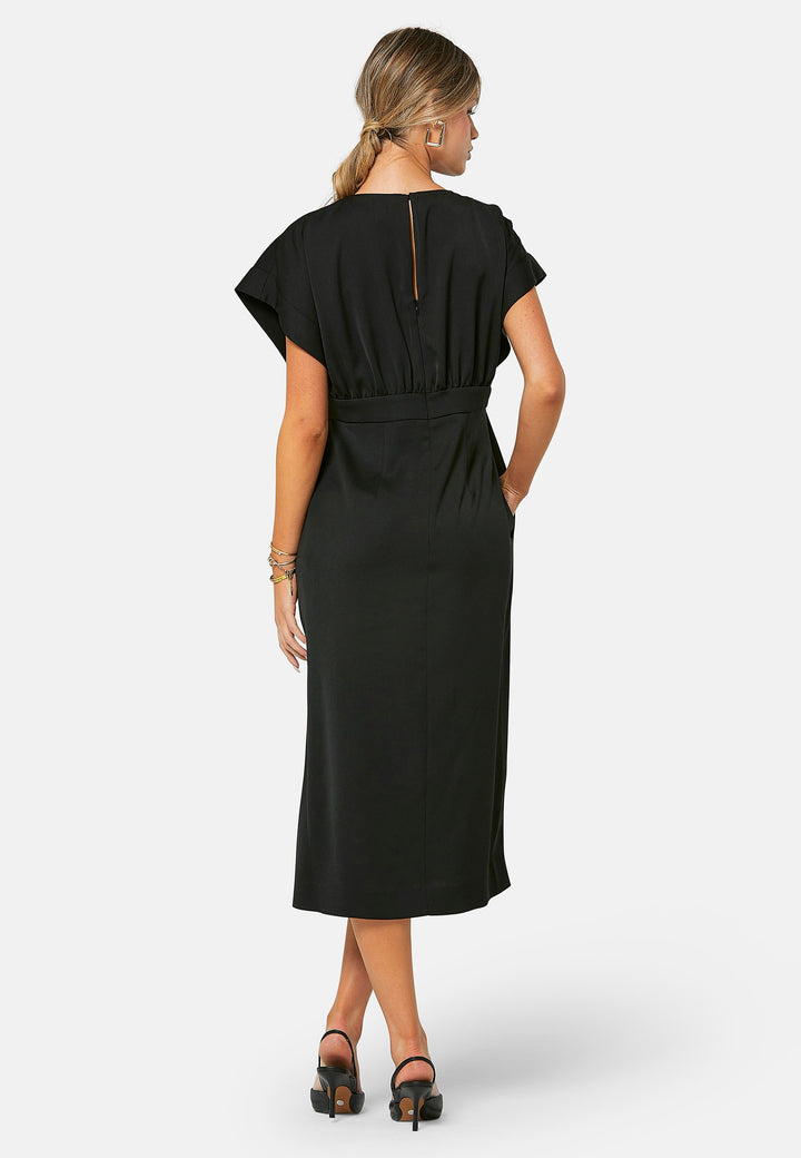 Elevate your wardrobe with Shiv, a simple black midi dress in a fluid satin back crepe. Featuring dropped sleeves, a gathered back waist seam, and a side slit for ease of movement. The back has a keyhole detail with a button closure.