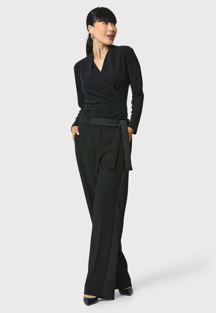 Introducing the Teagan Black Shimmer Top, a sophisticated boat neck blouse crafted from exquisite black jersey with a touch of glamour. This top effortlessly showcases timeless elegance and versatility, making it perfect for any occasion, whether a night out or a professional event.