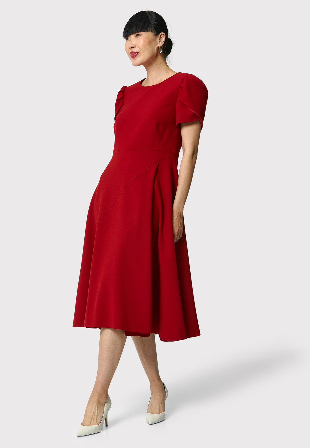 The Vera Garnet Red Dress is perfect for special occasions. It features a flattering fit-and-flare silhouette, a round neckline, and short puffed sleeves. The mid-calf length skirt flares out gracefully, adding elegance to the dress. Crafted from a comfortable fabric blend, it ensures ease of movement and a polished look.