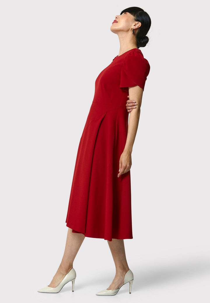 The Vera Garnet Red Dress is perfect for special occasions. It features a flattering fit-and-flare silhouette, a round neckline, and short puffed sleeves. The mid-calf length skirt flares out gracefully, adding elegance to the dress. Crafted from a comfortable fabric blend, it ensures ease of movement and a polished look.