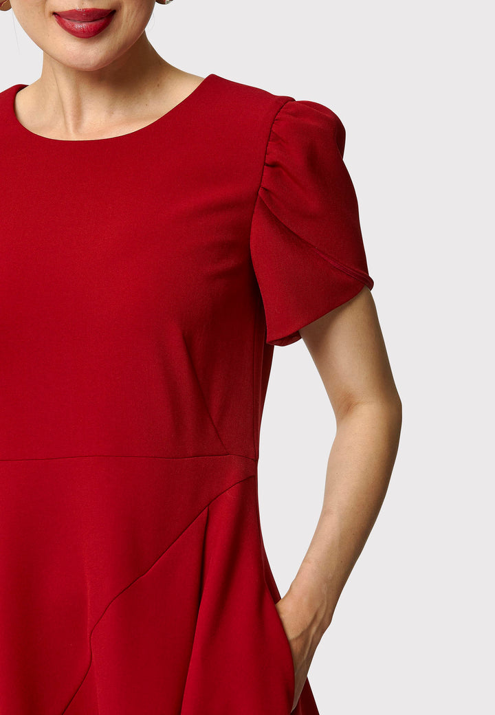 The Vera Garnet Red Dress is perfect for special occasions. It features a flattering fit-and-flare silhouette, a round neckline, and short puffed sleeves. The mid-calf length skirt flares out gracefully, adding elegance to the dress. Crafted from a comfortable fabric blend, it ensures ease of movement and a polished look.