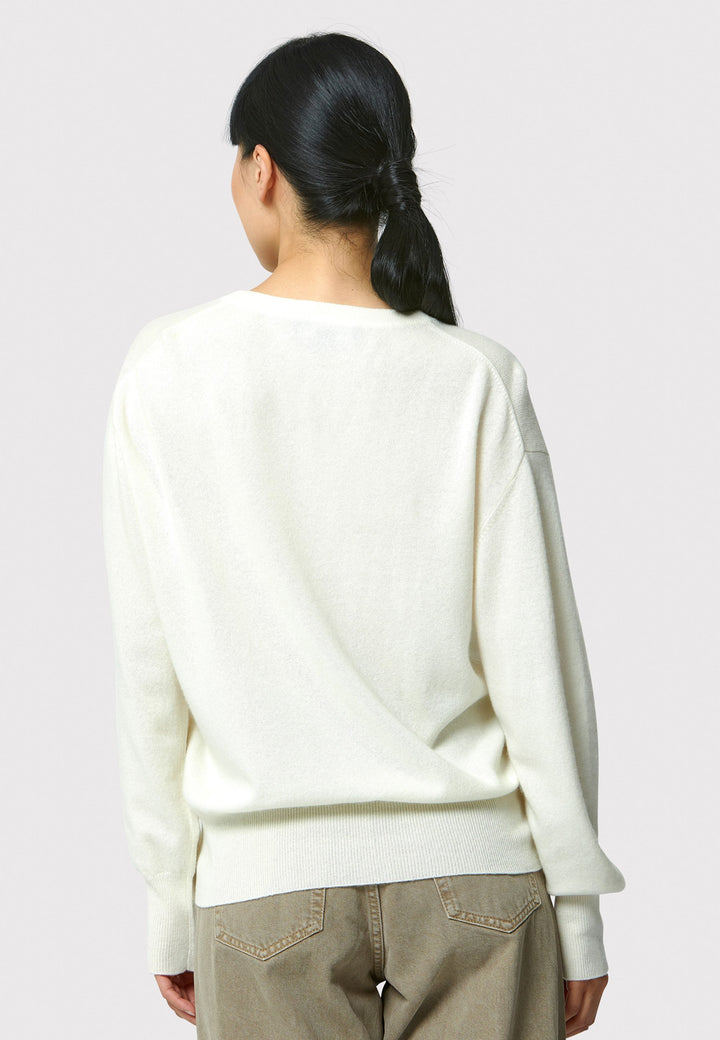 The Viv V-neck Cream Sweater is a luxurious blend of extra fine merino wool and cashmere, ensuring a soft and warm experience. 