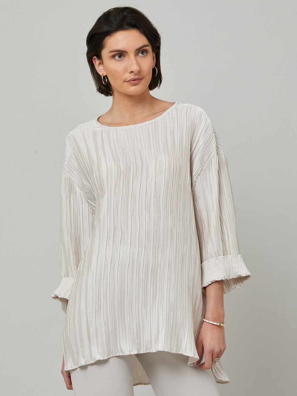 Hallie, elegant tunic in polished ivory pleated fabric. A simple wardrobe essential, the perfect foil for the matching Roz navy pleated skirt. Features full-length sleeve, shown here rolled up.